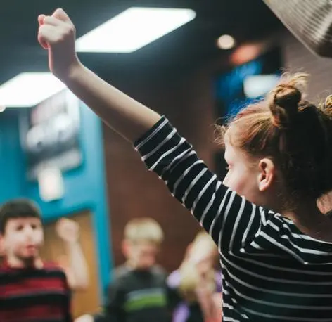 Children raising their hands during a lively class