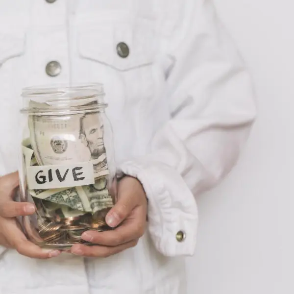 Hands holding a jar of money labelled Give